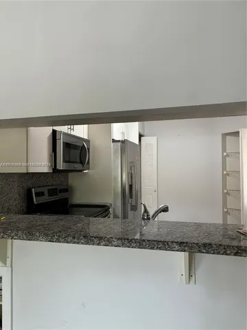 a view of a kitchen with granite countertop a sink and a stove