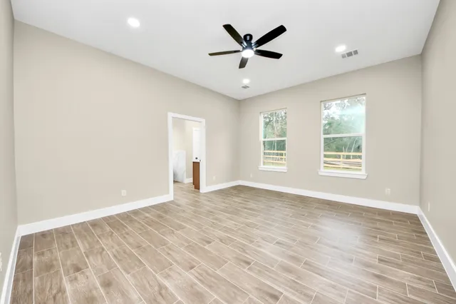 an empty room with wooden floor and windows