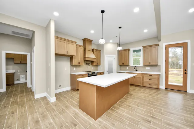 a large kitchen with stainless steel appliances a stove a sink dishwasher a refrigerator white cabinets and wooden floor next to a window