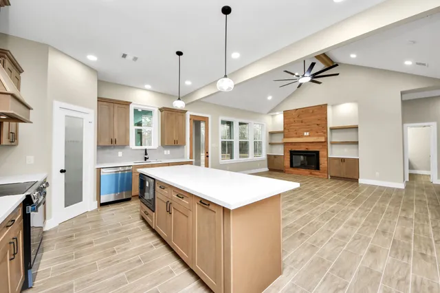 a large kitchen with kitchen island a stove a sink a center island and wooden floor