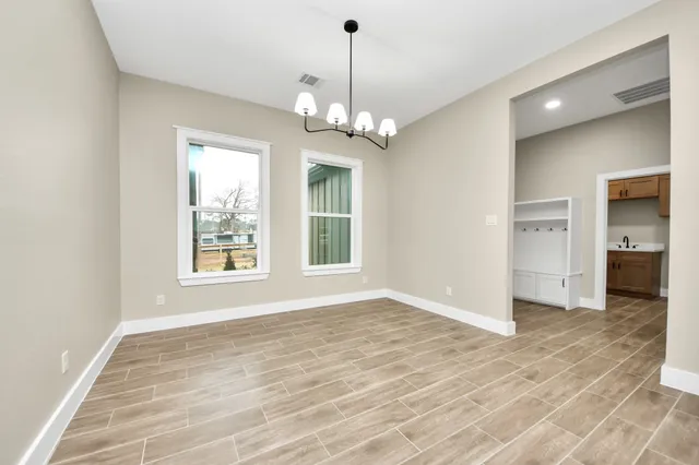 a view of an empty room with a window and wooden floor