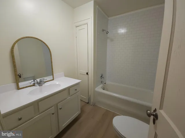 a bathroom with a granite countertop sink mirror bathtub and toilet