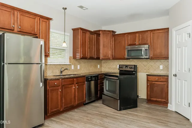 a kitchen with stainless steel appliances granite countertop a refrigerator stove a sink and dishwasher with wooden cabinet