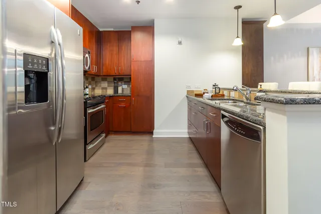 a kitchen with stainless steel appliances granite countertop a stove a refrigerator and a sink