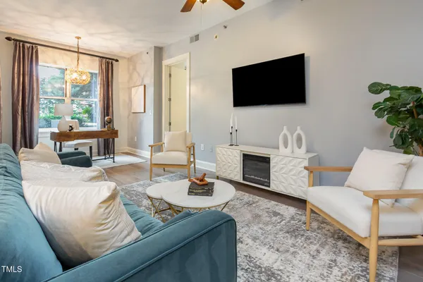 a living room with furniture a flat screen tv and a large window