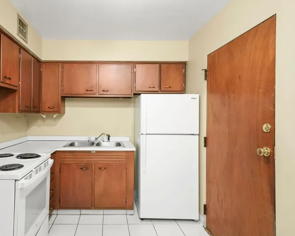 a kitchen with cabinets a stove top oven and white countertops
