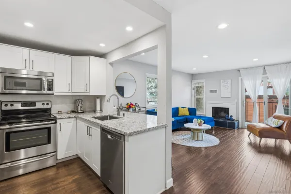 a kitchen with stainless steel appliances granite countertop a stove top oven a sink dishwasher and white cabinets with wooden floor