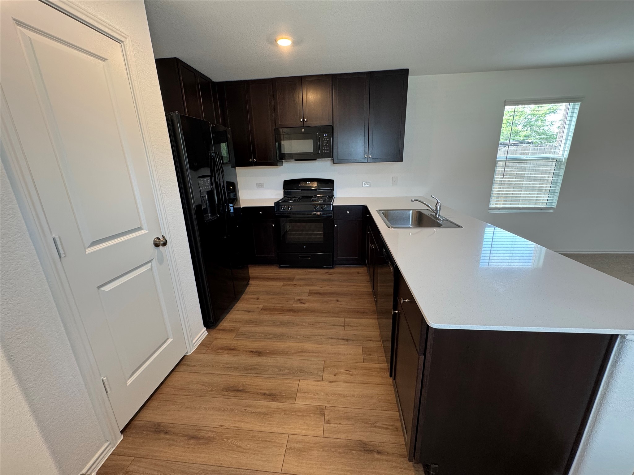 63 Trinity Circle Lockhart, TX 78644 - Photo 2 of 16 An inviting kitchen features a functional island with refrigerator and built-in microwave, pantry, dark cabinetry. and open to the living room