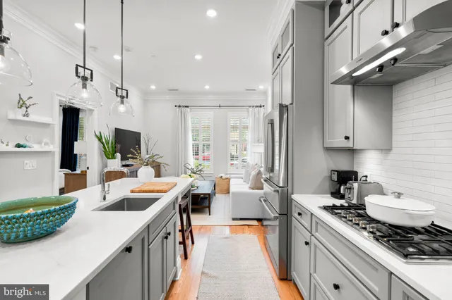 a large kitchen with kitchen island a large counter top space a sink stainless steel appliances and cabinets