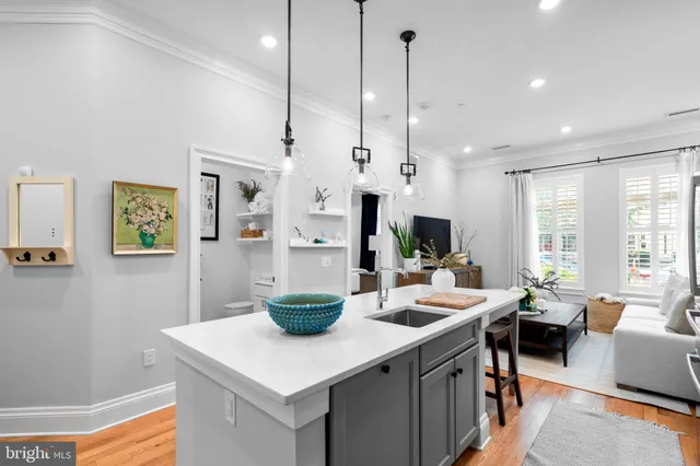 a room with stainless steel appliances kitchen island granite countertop a table chairs and a view of living room