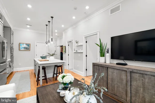 a living room with furniture kitchen view and a wooden floor