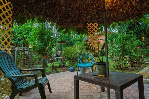 a backyard of a house with table and chairs under an umbrella