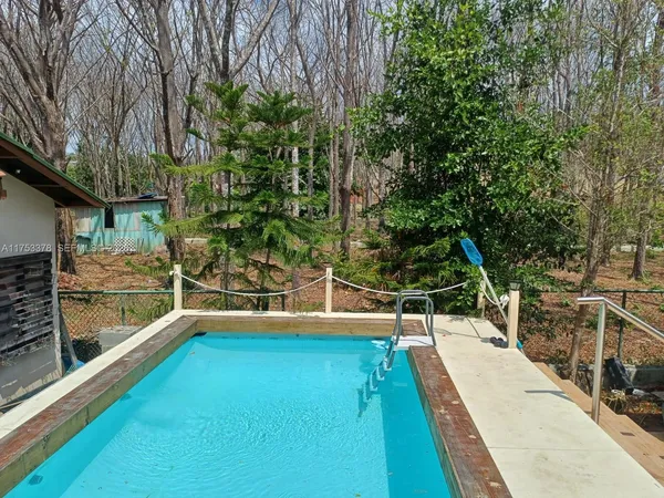 a view of a swimming pool with a patio and trees