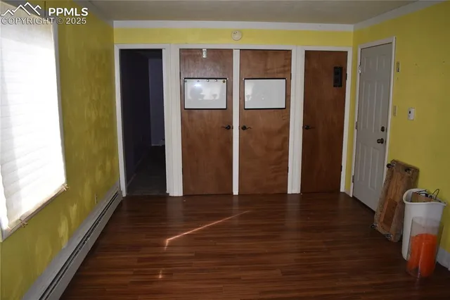 a view of an empty room with wooden floor and a bathroom