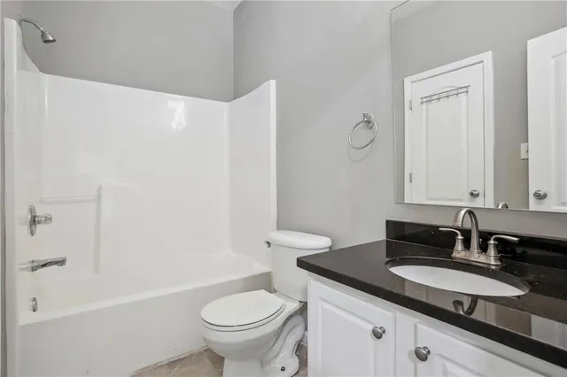 a bathroom with a granite countertop sink a toilet and bathtub