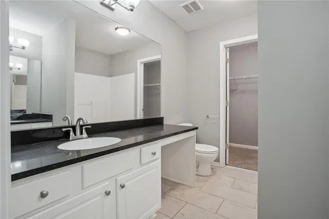a bathroom with a granite countertop sink a toilet and a mirror