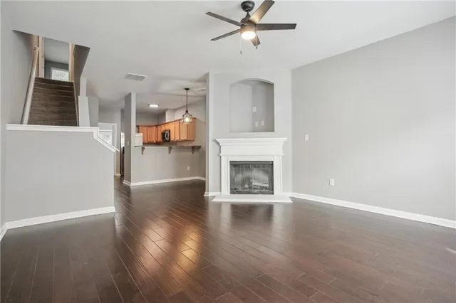 an empty room with wooden floor a ceiling fan and windows