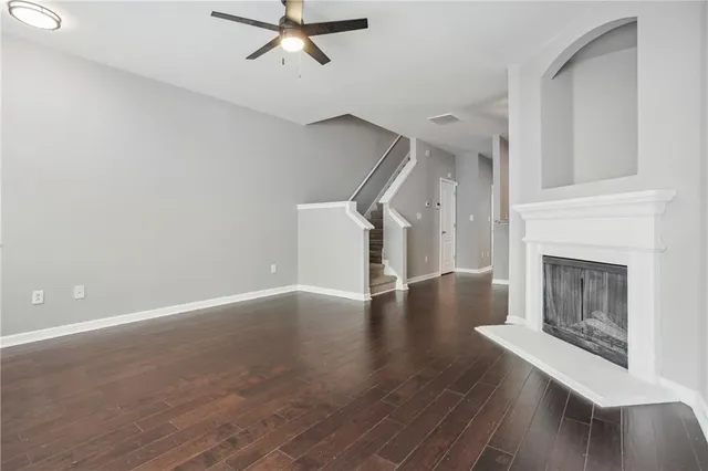 a view of an empty room with wooden floor fireplace and a window