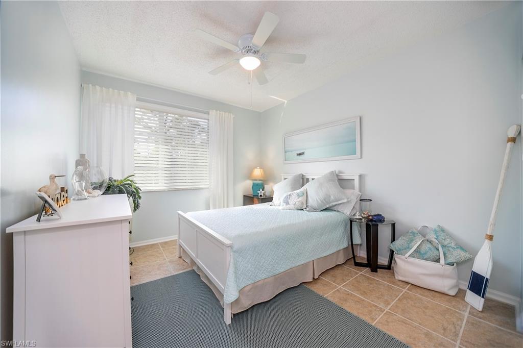 1160 Reserve Way, Unit 303 Naples, FL 34105 - Photo 9 of 19 a bedroom with a bed and a chandelier