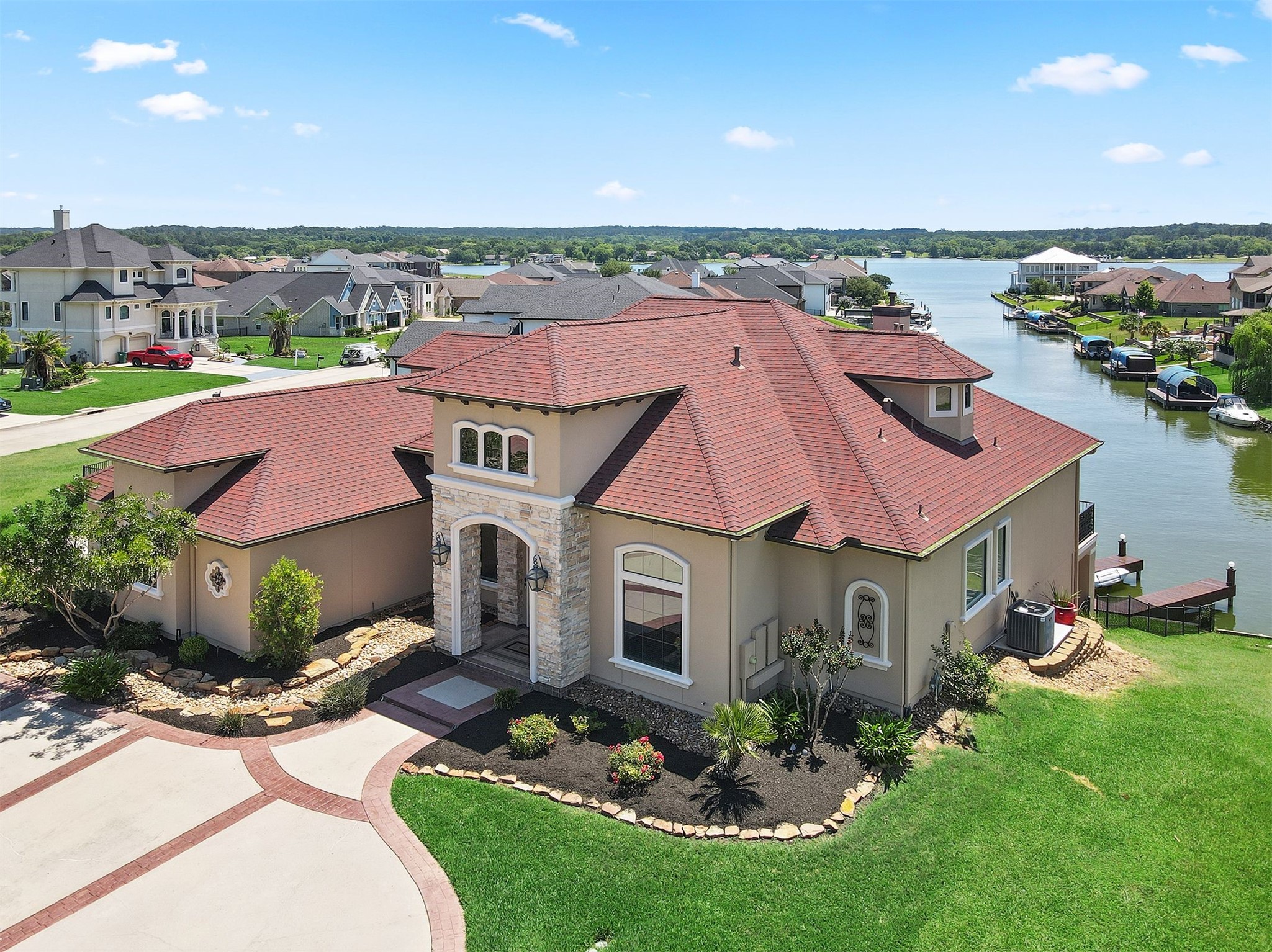 10896 Decatur Street Willis, TX 77318 - Photo 9 of 50 This stunning waterfront home boasts a modern design with a striking red-tiled roof and elegant stone accents, offering breathtaking canal views, lush landscaping, and a spacious, well-maintained driveway—perfect for those seeking a serene, picturesque setting.