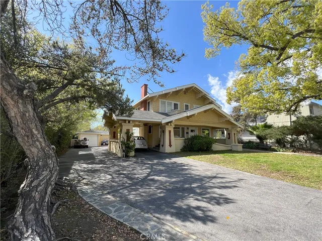 a front view of a house with a garden and trees