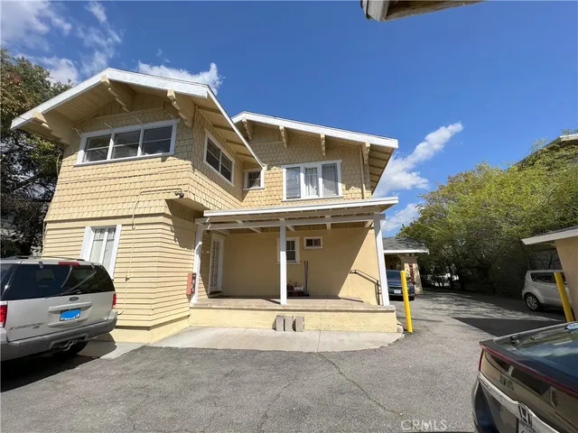 a view of a white house with a yard and potted plants
