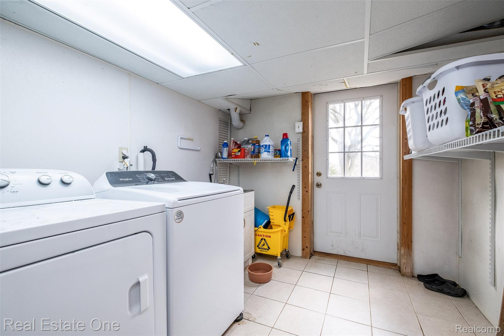 11030 Marshall Road South Lyon, MI 48178 - Photo 59 of 83 Utility space featuring a washer and dryer, tiled flooring, a rear door with multiple window panes, and wall-mounted shelving