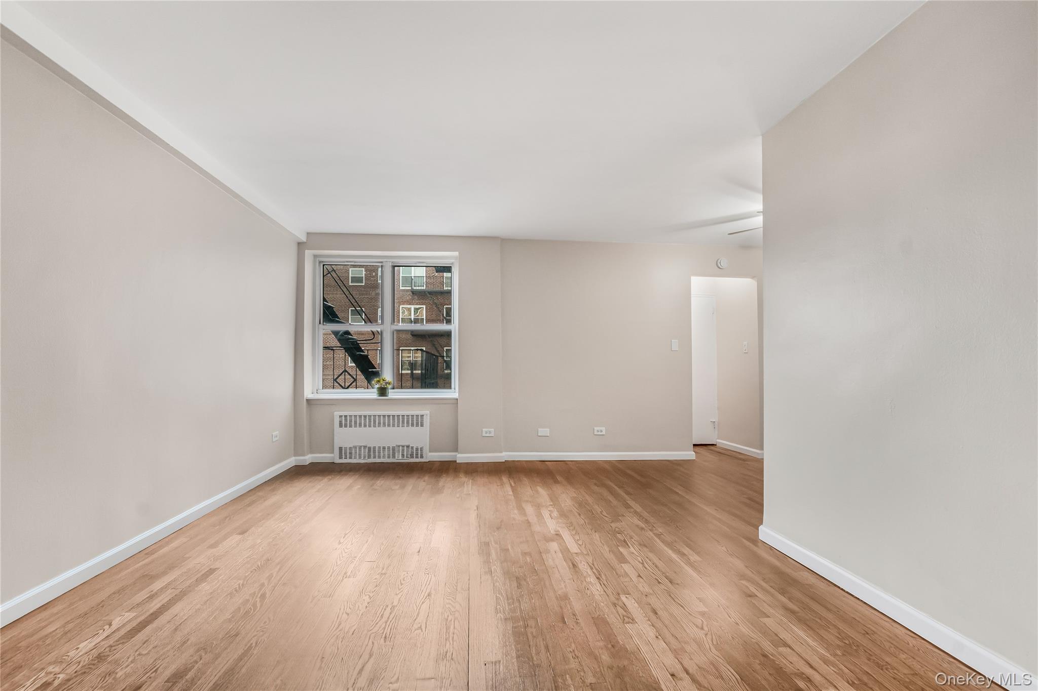 84-50 169th Street, Unit 418 Queens, NY 11432 - Photo 12 of 15 Unfurnished room featuring radiator and light wood-style floors