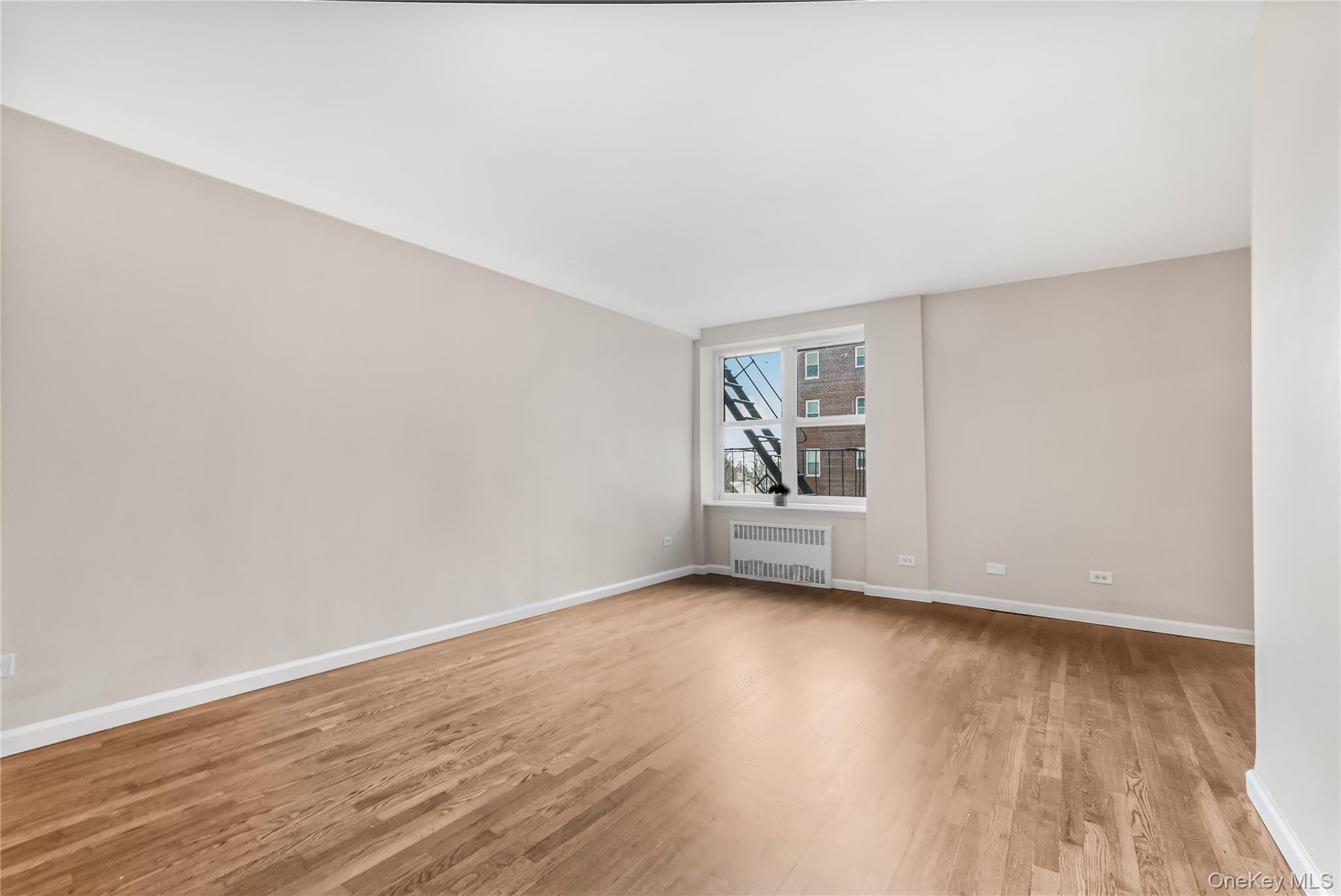 84-50 169th Street, Unit 418 Queens, NY 11432 - Photo 6 of 15 Spare room with light wood finished floors and radiator