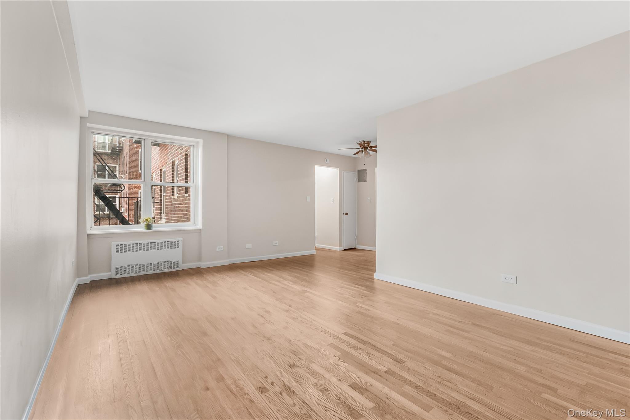 84-50 169th Street, Unit 418 Queens, NY 11432 - Photo 7 of 15 Unfurnished room featuring radiator heating unit and light wood-style flooring