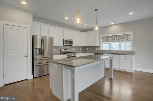 a kitchen with stainless steel appliances granite countertop a sink a stove a refrigerator and cabinets