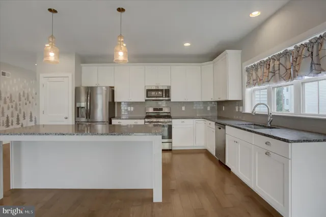a kitchen with stainless steel appliances granite countertop a sink a stove and a refrigerator