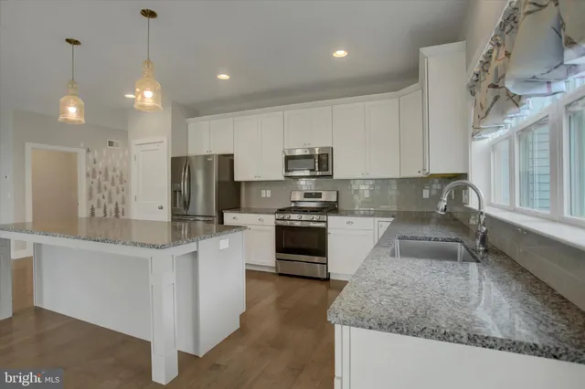 a kitchen with granite countertop a stove a sink and a wooden floor