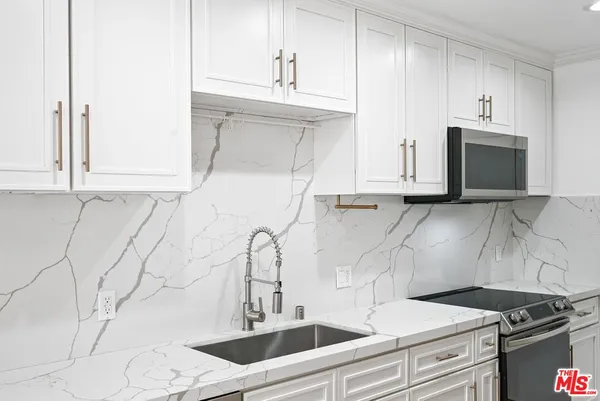 a kitchen with granite countertop white cabinets and stainless steel appliances
