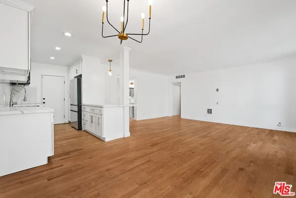 a view of kitchen and empty room with wooden floor