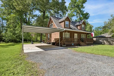 a view of a house with a yard and large tree