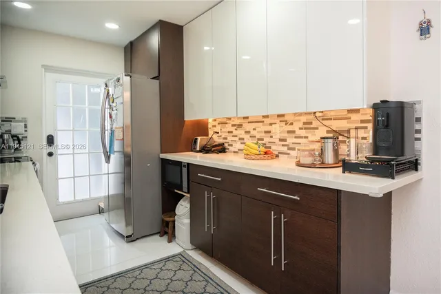 a kitchen with stainless steel appliances kitchen island granite countertop a refrigerator and a sink