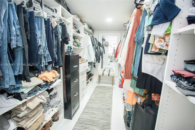 a view of walk in closet with clothes and shoes