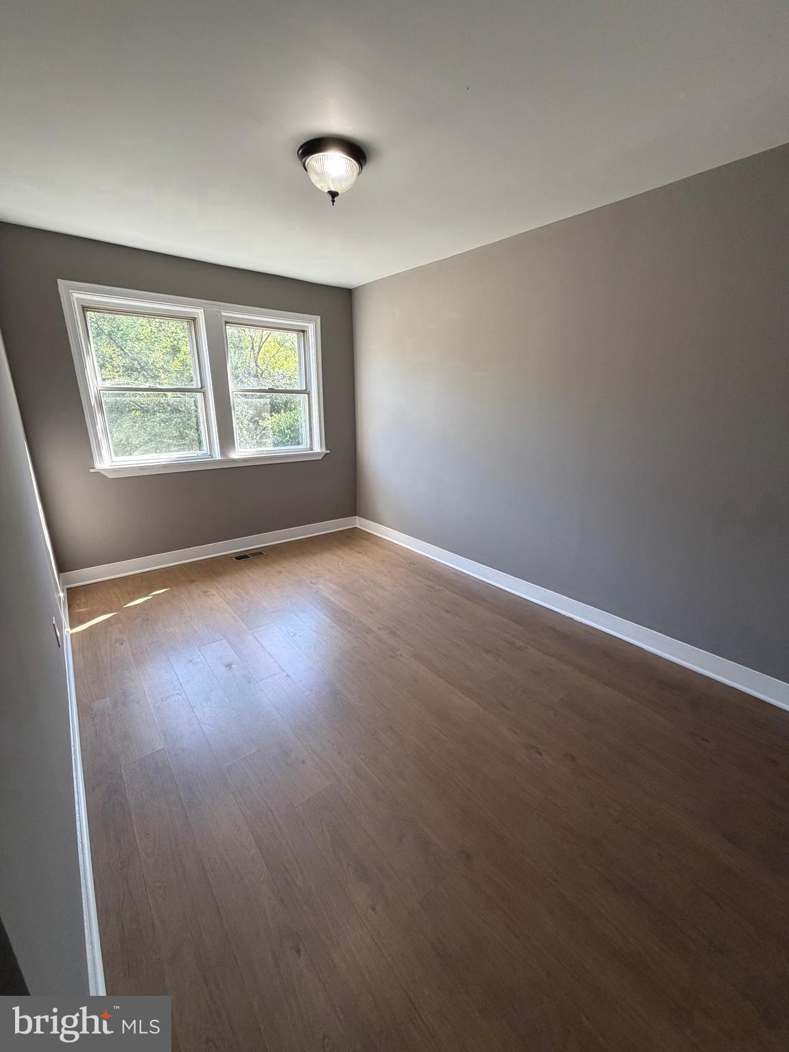 1353 Cambria Street Baltimore, MD 21225 - Photo 9 of 23 an empty room with wooden floor and windows
