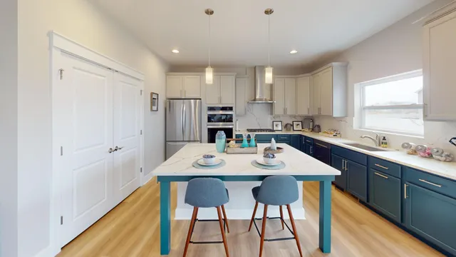 a kitchen with stainless steel appliances kitchen island granite countertop a table chairs sink and cabinets