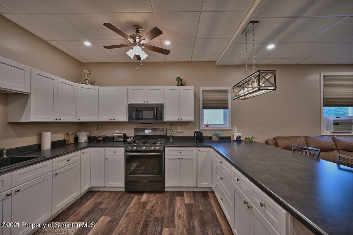 303 Main Street Nicholson, PA 18446 - Photo 9 of 98 a kitchen with a sink dishwasher a stove and white cabinets with wooden floor