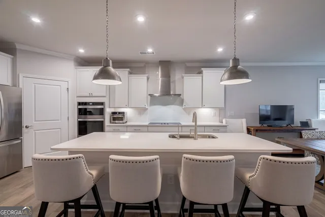 a living room with stainless steel appliances furniture dining table and wooden floor