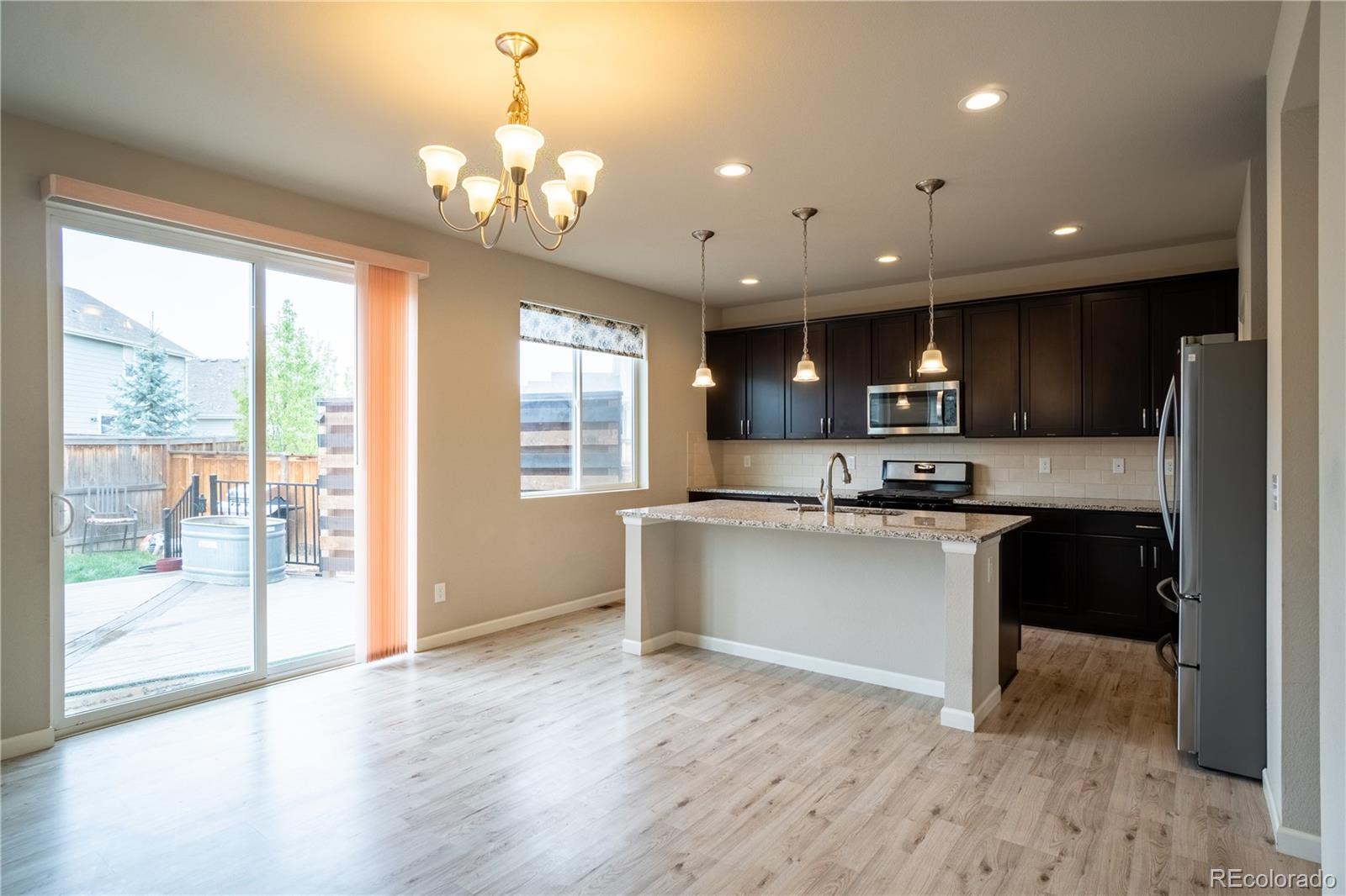 643 Ranchhand Drive Berthoud, CO 80513 - Photo 11 of 39 a kitchen with stainless steel appliances granite countertop a refrigerator a sink dishwasher a stove and a dining table with wooden floor