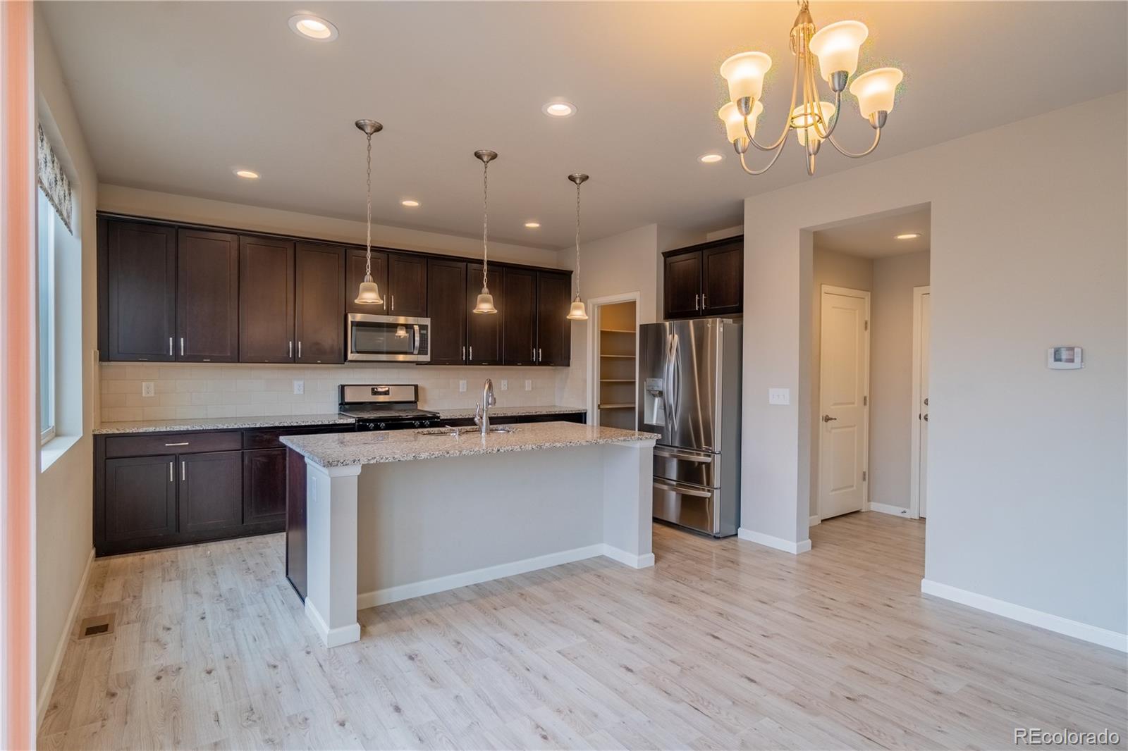 643 Ranchhand Drive Berthoud, CO 80513 - Photo 6 of 39 a kitchen with kitchen island stainless steel appliances cabinets a sink and a counter top space