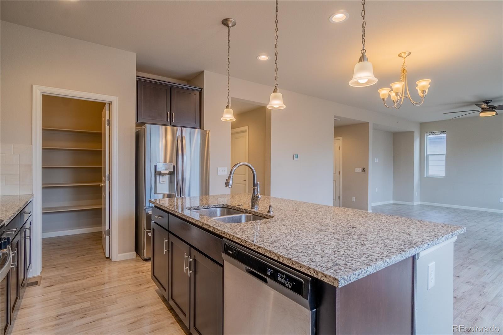 643 Ranchhand Drive Berthoud, CO 80513 - Photo 7 of 39 a kitchen with kitchen island granite countertop a wooden floor and a sink