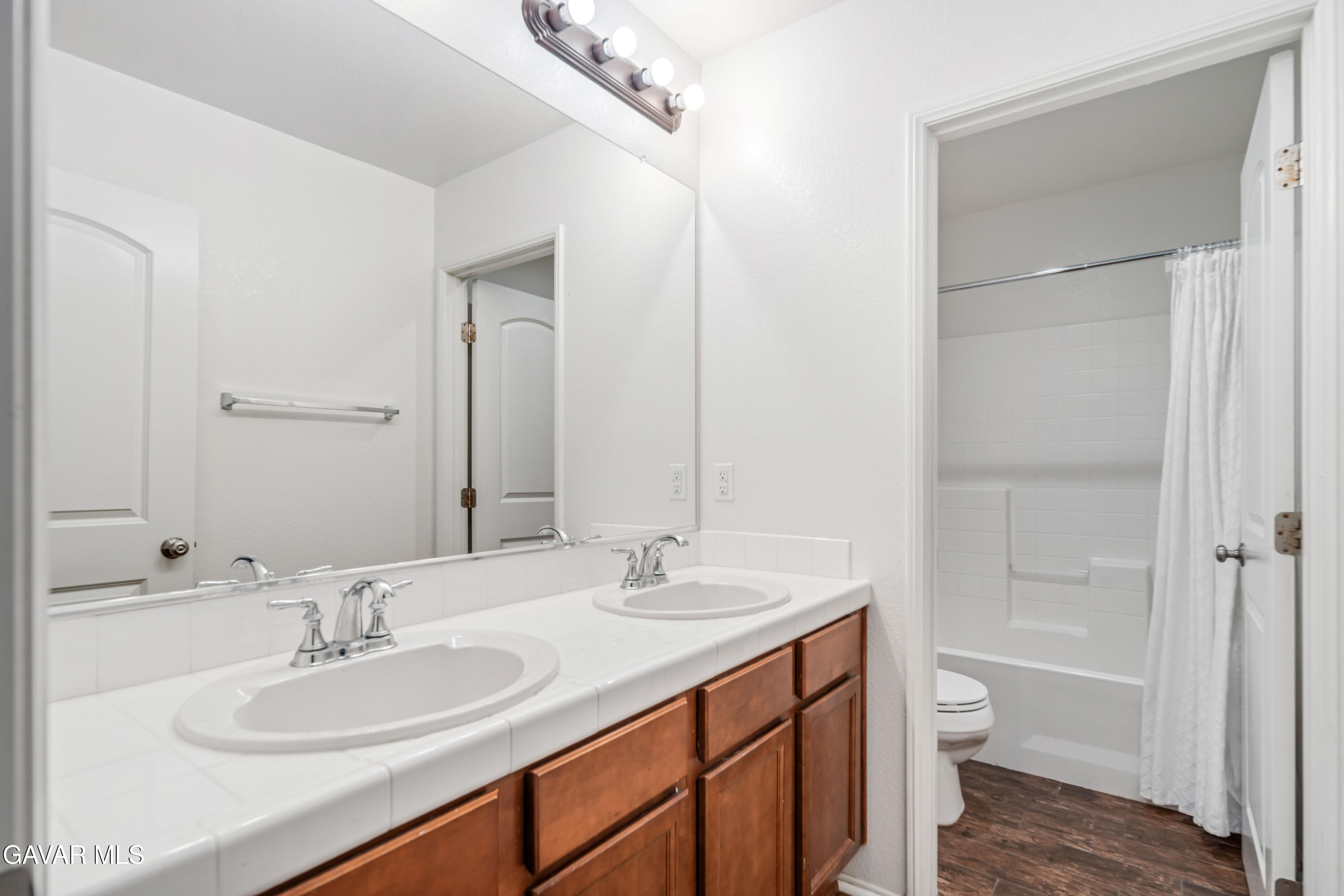3024 Erica Avenue Rosamond, CA 93560 - Photo 26 of 32 a bathroom with a sink a toilet and a large mirror