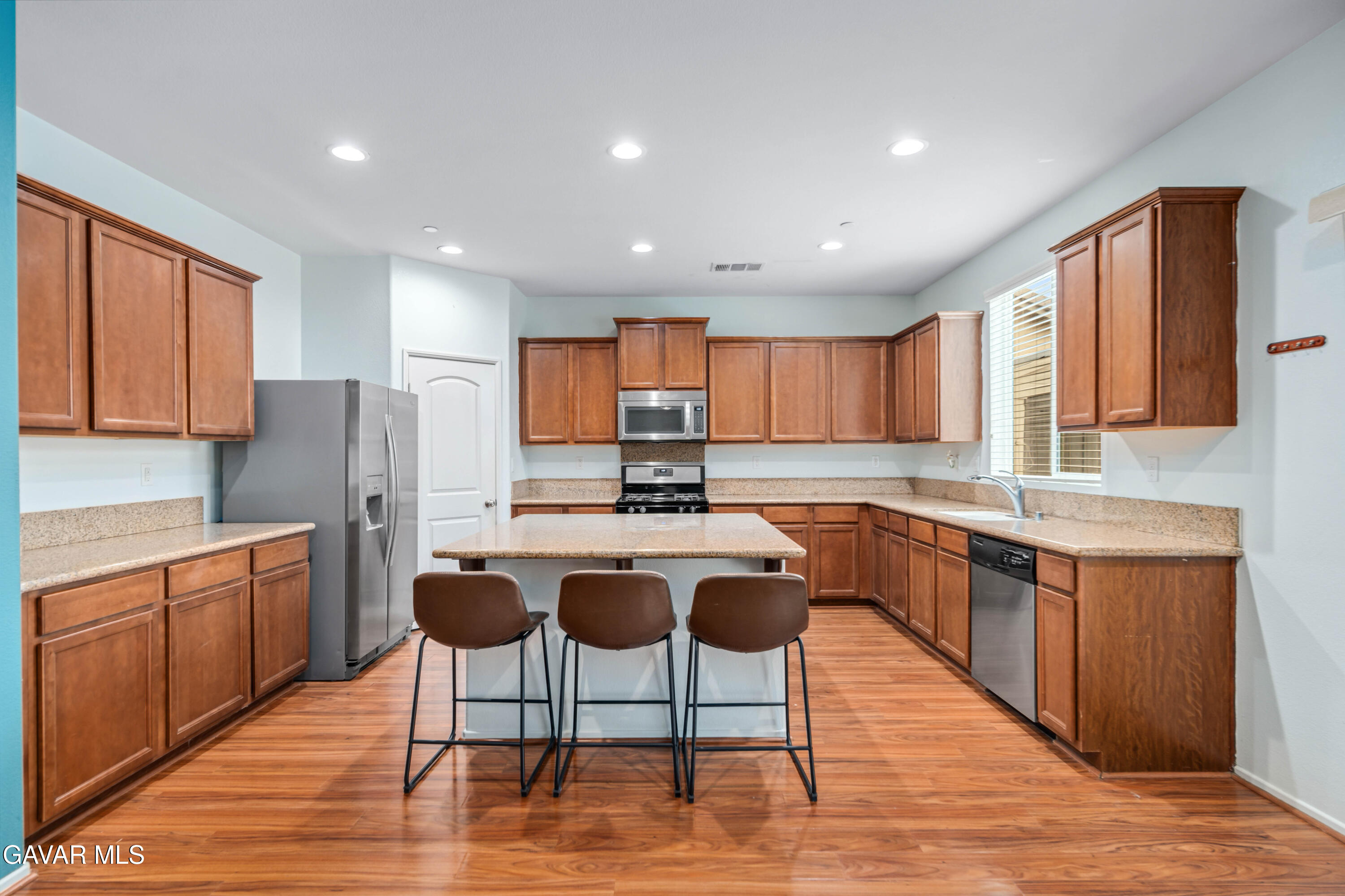 3024 Erica Avenue Rosamond, CA 93560 - Photo 8 of 32 a kitchen with stainless steel appliances granite countertop wooden floor a stove a sink dishwasher and a refrigerator with wooden floor