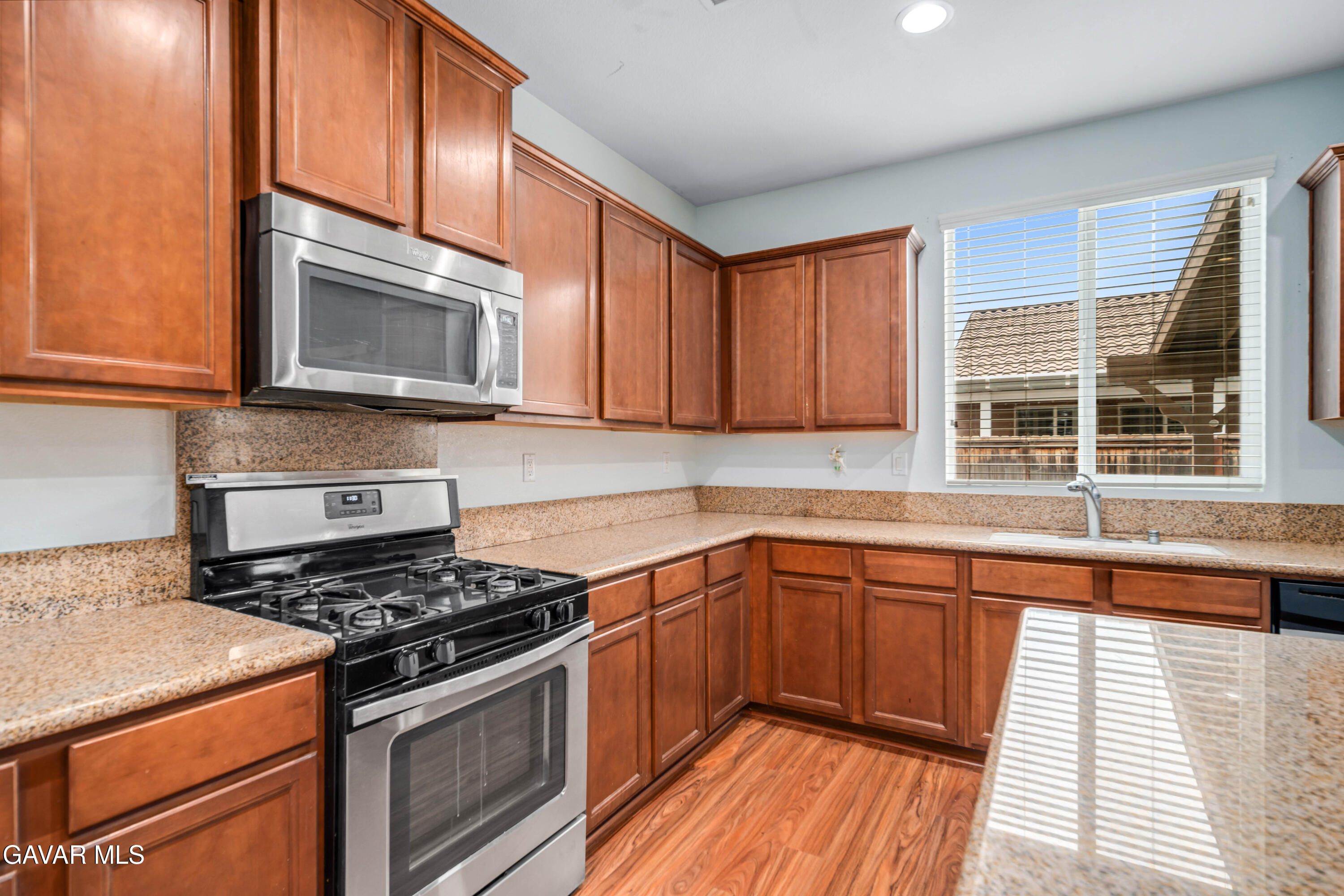 3024 Erica Avenue Rosamond, CA 93560 - Photo 9 of 32 a kitchen with stainless steel appliances granite countertop a stove microwave and sink