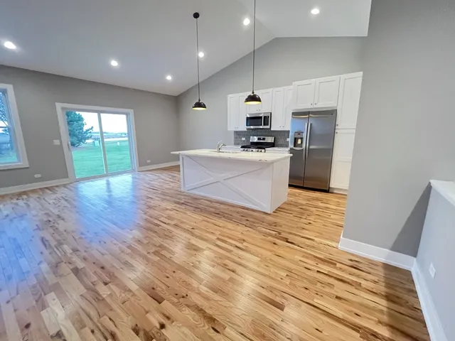 a view of kitchen with microwave a refrigerator and wooden floor