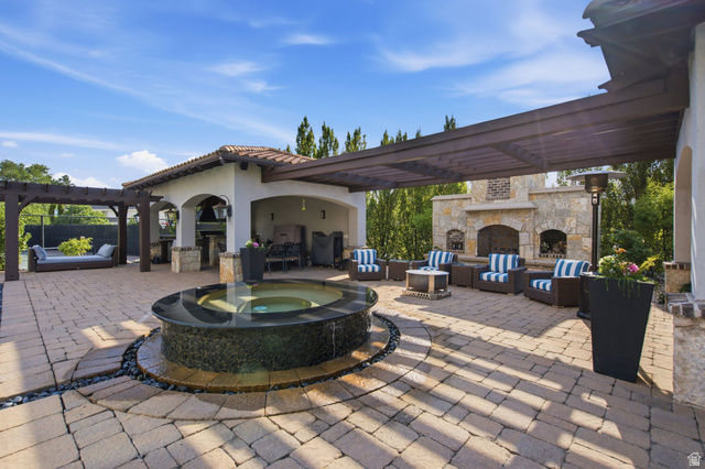 12308 Mariah Circle Draper, UT 84020 - Photo 138 of 293 Expansive paver patio with a central water feature, covered outdoor kitchen, stone fireplace, and a large pergola